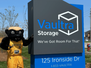 Grand opening event at Vaultra Storage Brampton with a friendly honey badger mascot interacting with guests, festive decorations, balloons, and a ribbon-cutting area, creating a welcoming and lively atmosphere.